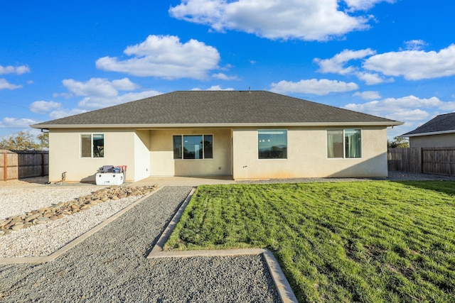 rear view of property with a fenced backyard, a shingled roof, stucco siding, a patio area, and a lawn