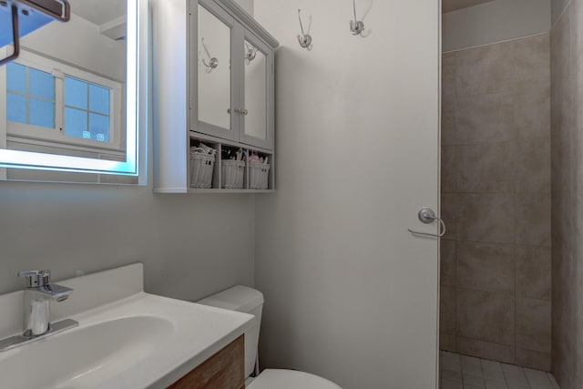 bathroom featuring tiled shower, toilet, and vanity