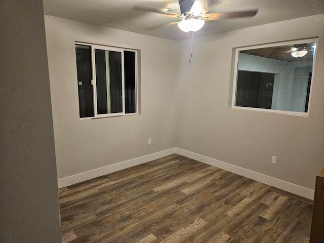 spare room featuring baseboards, ceiling fan, and dark wood finished floors