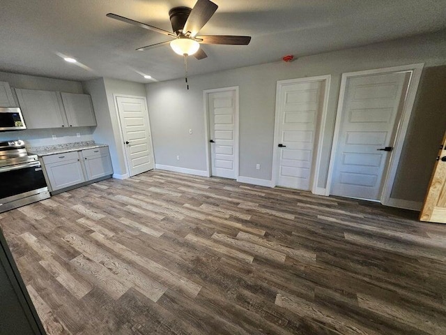 kitchen with baseboards, light countertops, wood finished floors, stainless steel appliances, and a ceiling fan