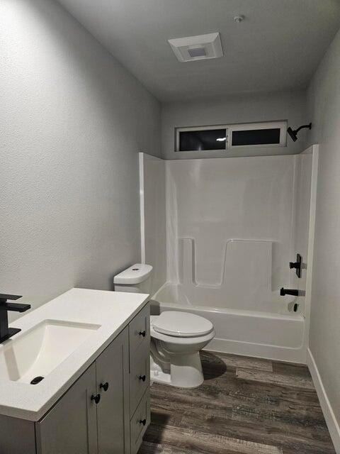 full bath with toilet, wood finished floors, tub / shower combination, baseboards, and vanity