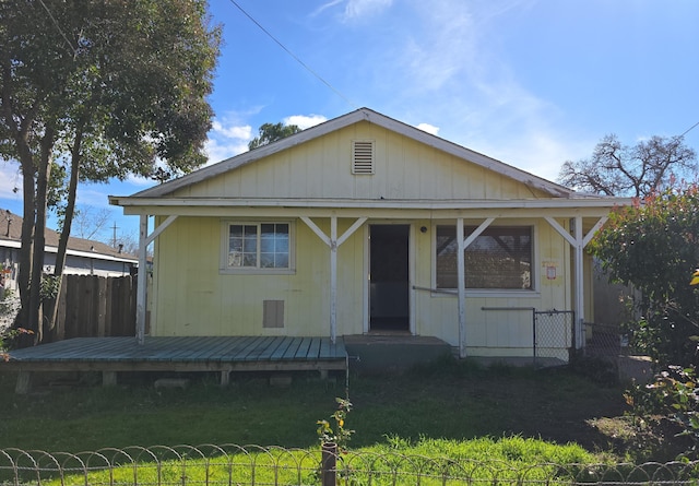 view of front facade featuring a deck, a front lawn, and fence