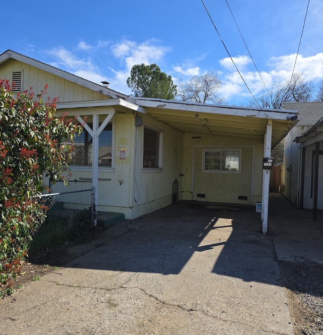 rear view of house featuring an attached carport, fence, and driveway