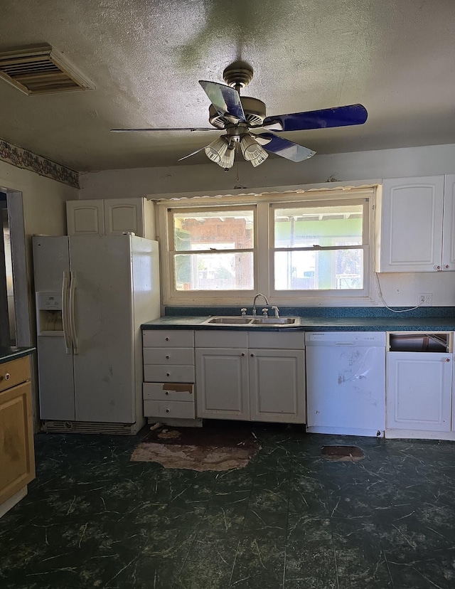 kitchen with dark countertops, visible vents, white appliances, and a sink