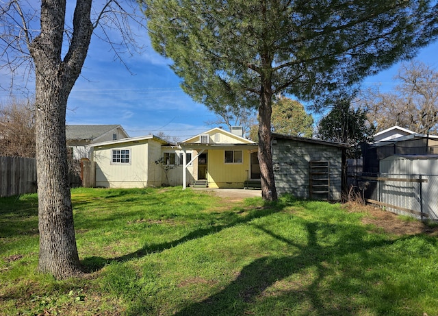 rear view of house with entry steps, fence, a lawn, and crawl space