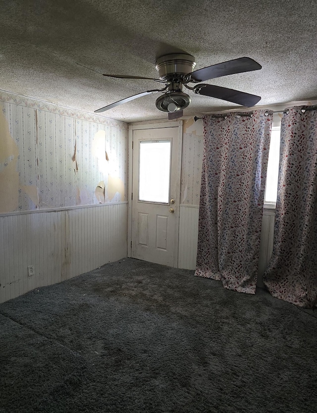 carpeted spare room with a textured ceiling and ceiling fan