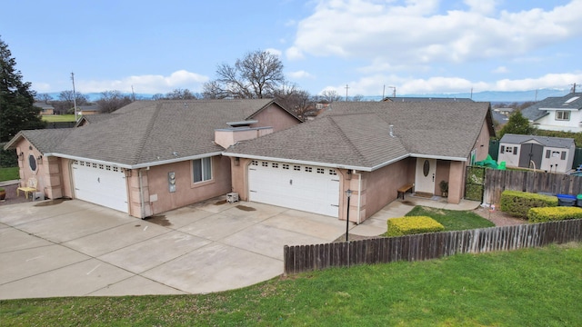 view of front of home with fence, concrete driveway, roof with shingles, stucco siding, and a garage