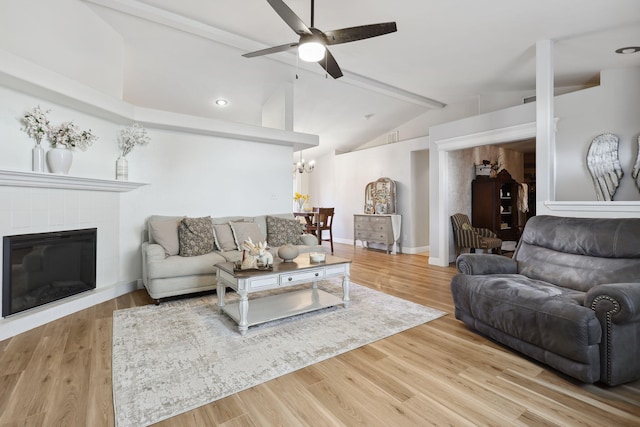 living area with ceiling fan with notable chandelier, vaulted ceiling with beams, baseboards, and wood finished floors