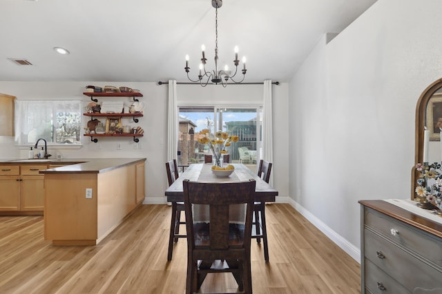 dining area featuring baseboards, plenty of natural light, a notable chandelier, and light wood-style flooring