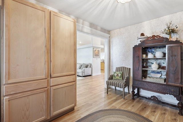 living area with light wood-type flooring and wallpapered walls