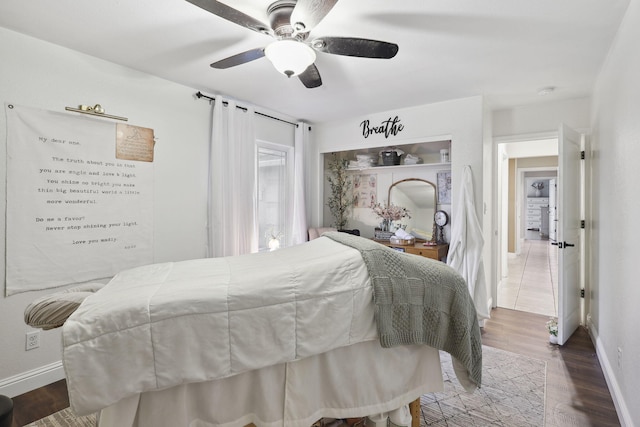 bedroom with ceiling fan, baseboards, and wood finished floors