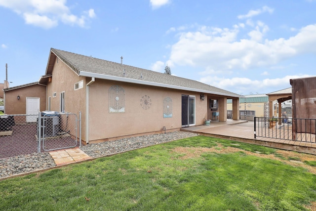 rear view of house featuring stucco siding, a lawn, fence, and a gate