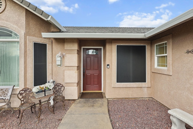 property entrance featuring stucco siding and roof with shingles