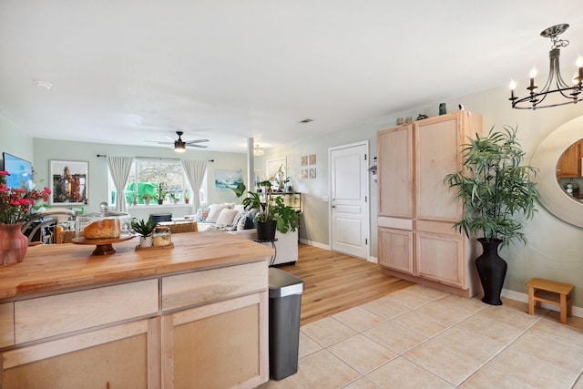 kitchen featuring butcher block countertops, open floor plan, light brown cabinets, and ceiling fan with notable chandelier