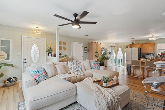 living area featuring light wood finished floors and ceiling fan with notable chandelier