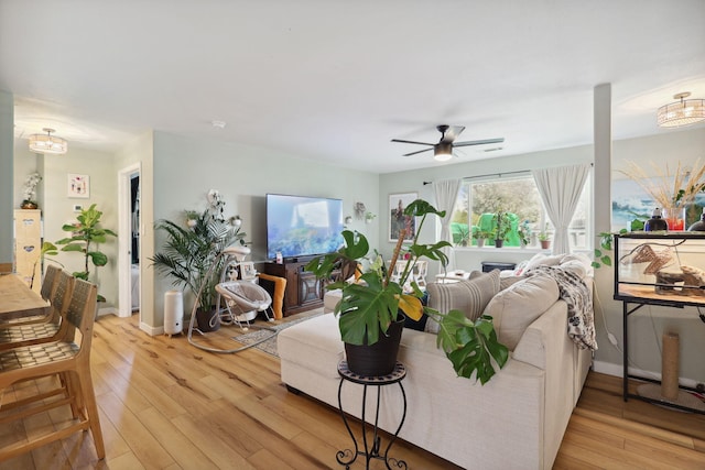 living room with baseboards, light wood-style floors, and ceiling fan