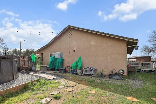 back of property featuring stucco siding, a yard, and fence