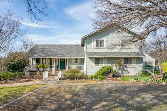 traditional-style home featuring covered porch and a shingled roof