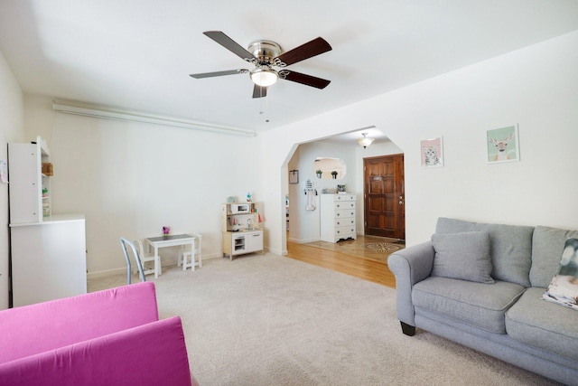 living area with arched walkways, carpet floors, and ceiling fan