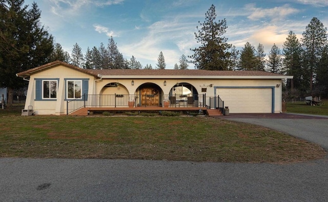 view of front of home with aphalt driveway, a garage, stucco siding, and a front lawn