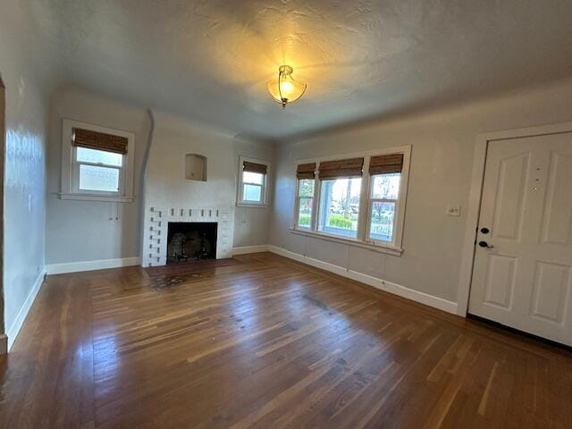 unfurnished living room with a fireplace, baseboards, and wood finished floors