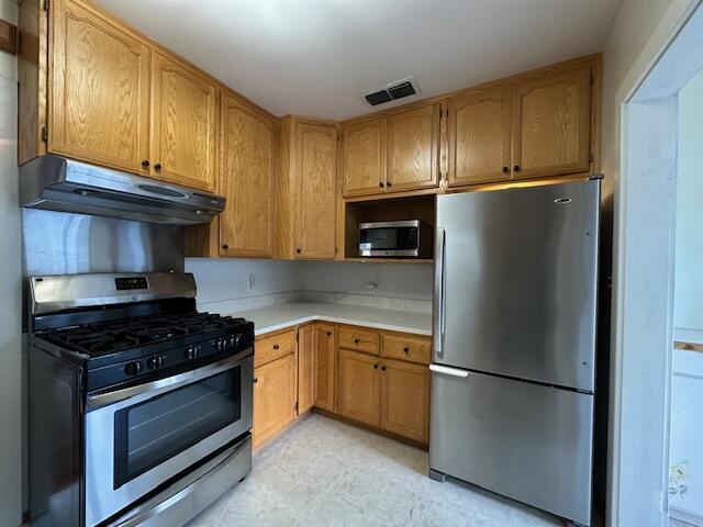 kitchen featuring light floors, visible vents, stainless steel appliances, light countertops, and under cabinet range hood