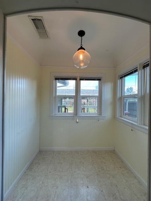 empty room with a wealth of natural light, visible vents, and baseboards