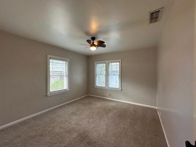 carpeted spare room with visible vents, baseboards, and ceiling fan