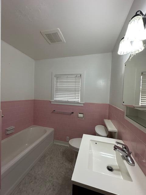 full bath featuring visible vents, toilet, a garden tub, tile walls, and tile patterned flooring