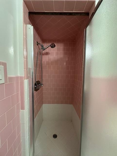 full bathroom with tile walls and a shower stall