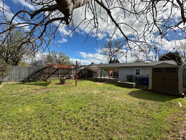 view of yard with a fenced backyard, a storage unit, and an outdoor structure