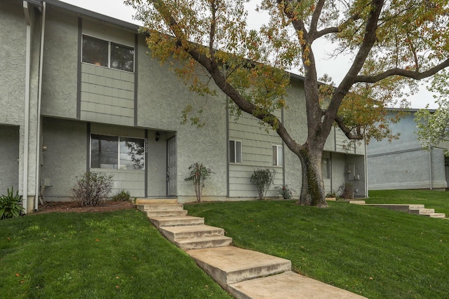 view of front of house with stucco siding and a front yard