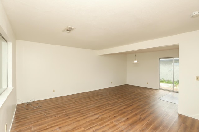 spare room with visible vents, baseboards, and wood finished floors