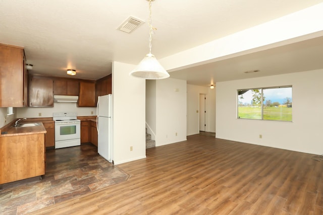 kitchen with visible vents, under cabinet range hood, dark wood finished floors, open floor plan, and white appliances