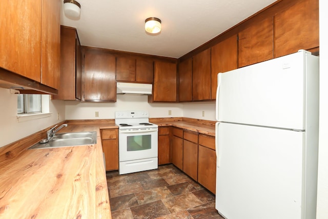 kitchen with butcher block countertops, under cabinet range hood, stone finish flooring, a sink, and white appliances