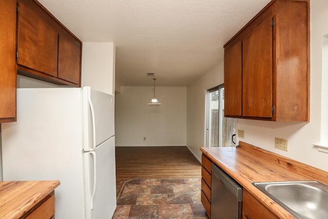 kitchen featuring a sink, wood counters, freestanding refrigerator, and stainless steel dishwasher