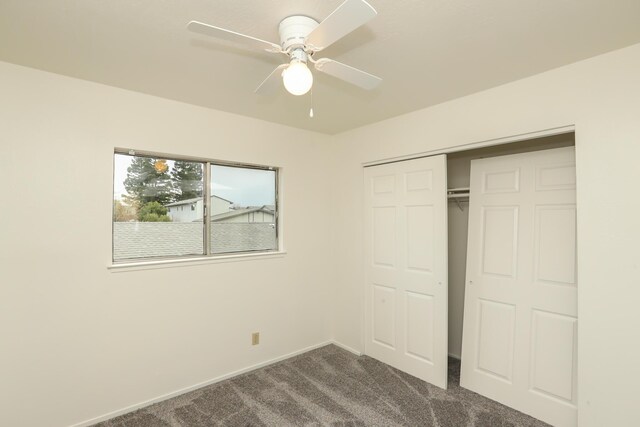 unfurnished bedroom with a closet, baseboards, ceiling fan, and dark carpet