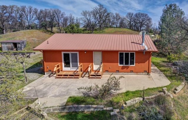 back of house with entry steps, a patio area, metal roof, and crawl space