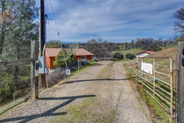 view of road with gravel driveway and a gated entry