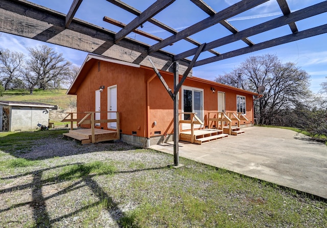 back of property with stucco siding, a patio area, a pergola, and crawl space