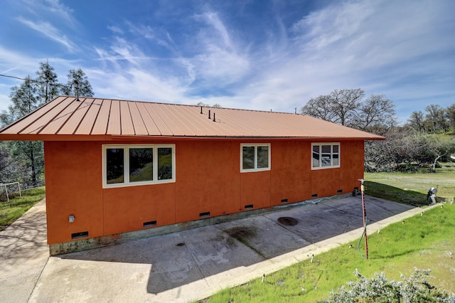 view of side of property with crawl space, a yard, and metal roof