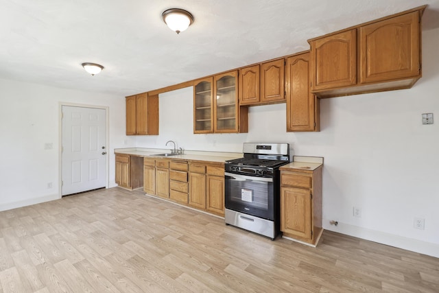 kitchen featuring a sink, brown cabinets, stainless steel range with gas cooktop, and light countertops