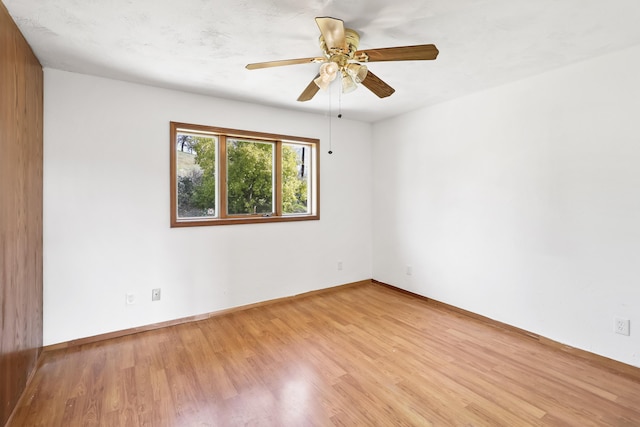 spare room featuring baseboards, wood finished floors, and a ceiling fan