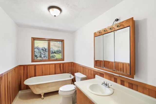 bathroom featuring a freestanding tub, toilet, wood walls, and wainscoting