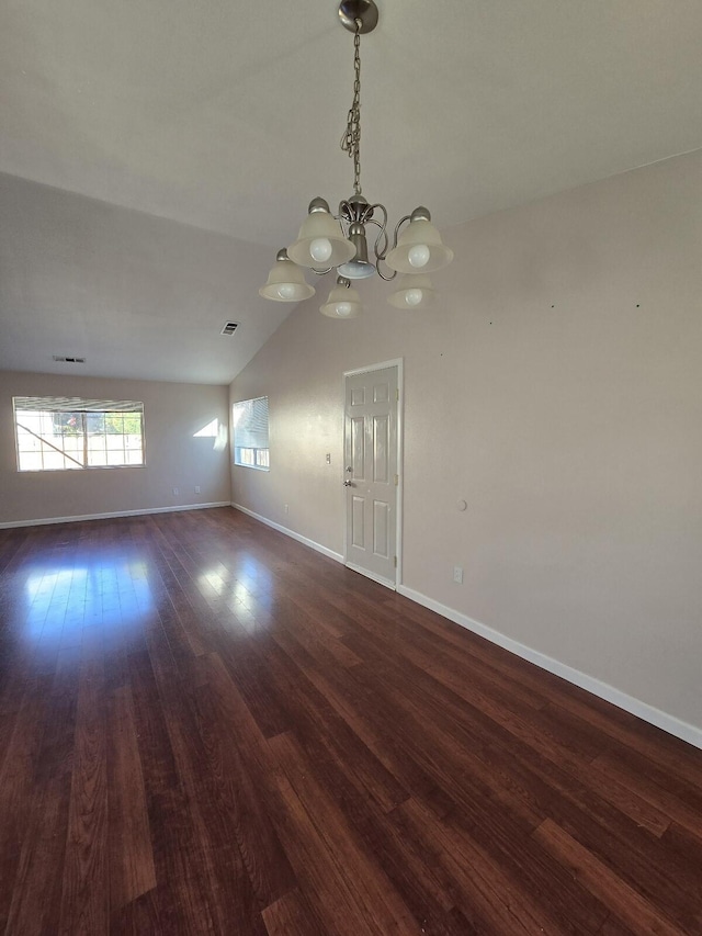 empty room with visible vents, dark wood-style floors, baseboards, a chandelier, and vaulted ceiling