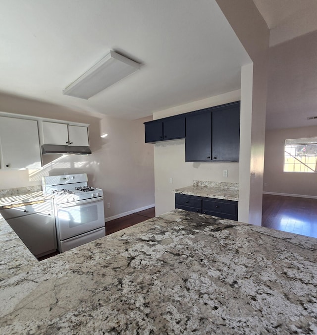 kitchen featuring white gas stove, dark wood finished floors, baseboards, and light stone counters