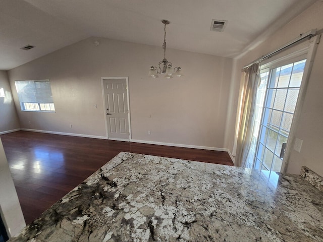 spare room featuring an inviting chandelier, wood finished floors, visible vents, and vaulted ceiling