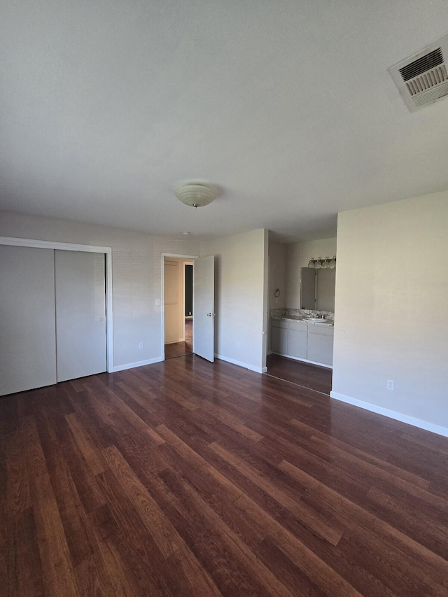 unfurnished living room with baseboards, visible vents, and dark wood-style flooring