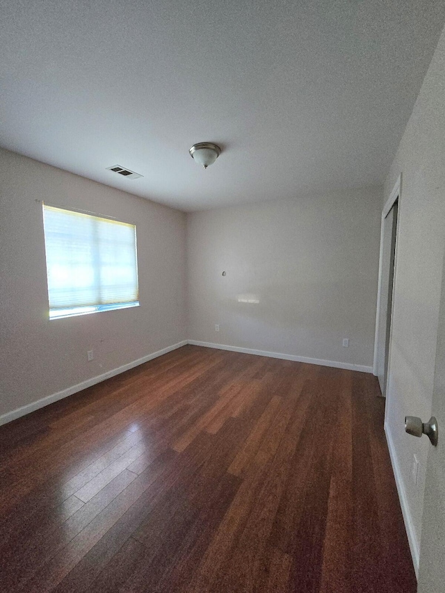 unfurnished room featuring visible vents, baseboards, and wood finished floors