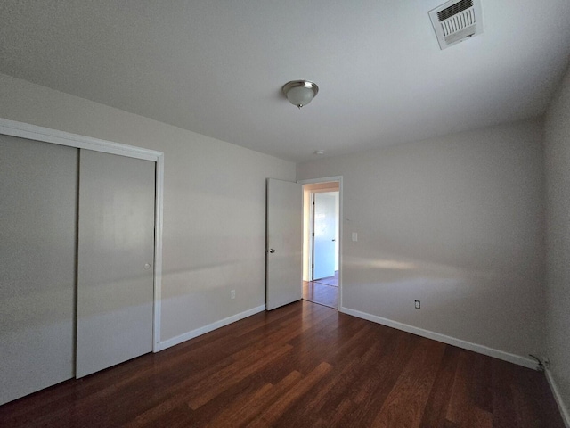 unfurnished bedroom with a closet, visible vents, baseboards, and wood finished floors